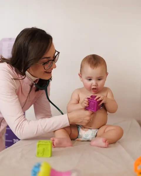 Dra. Ana Bürger brincando com um bebê durante o exame